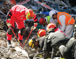 Crews wearing high visibility gear and hard hats work to break through the rubble left after the Christchurch Earthquake.