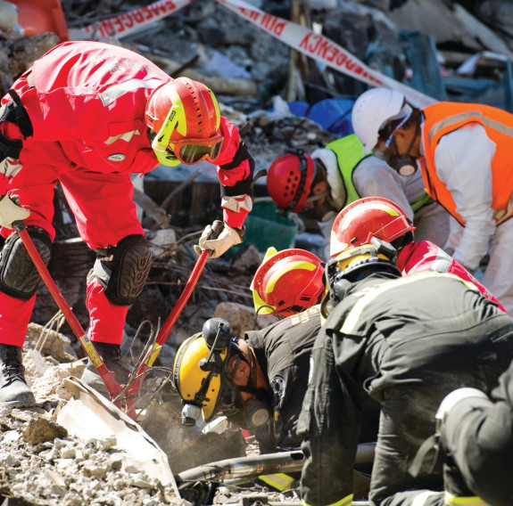 Crews wearing high visibility gear and hard hats work to break through the rubble left after the Christchurch Earthquake.