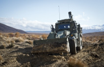 A green New Zealand Army High Mobility Engineer Excavator (Combat Tractor) moves dirt around in the Waiouru Military Training Area