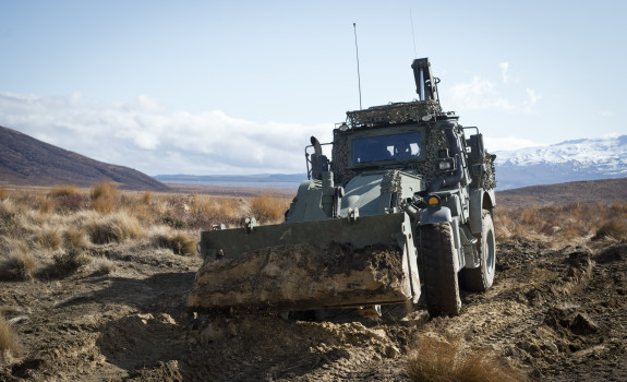 A green New Zealand Army High Mobility Engineer Excavator (Combat Tractor) moves dirt around in the Waiouru Military Training Area