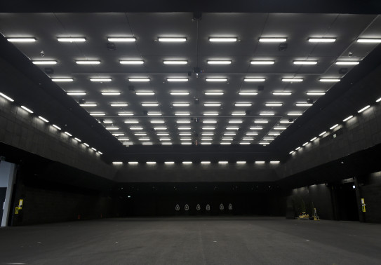 A vary dark room with a number of lights on the ceiling and targets in the background