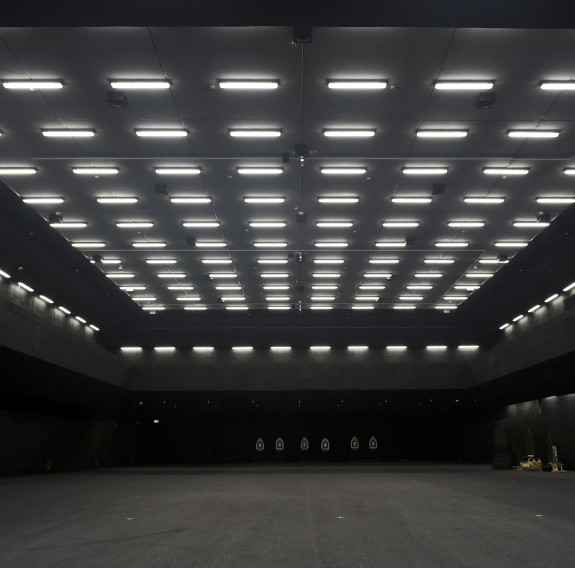 A vary dark room with a number of lights on the ceiling and targets in the background