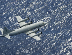 A Royal New Zealand Air Force Orion flies over the blue ocean
