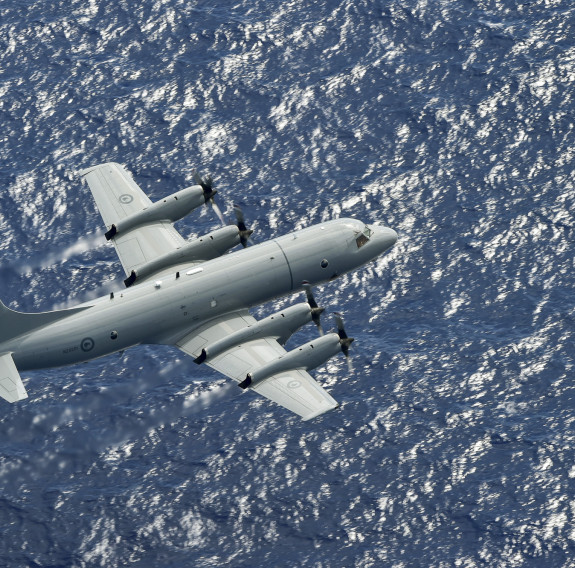 A Royal New Zealand Air Force Orion flies over the blue ocean