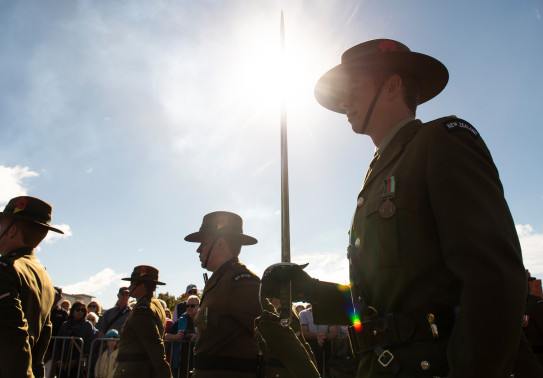 New Zealand Army soldiers as part of a Royal Guard of Honour for Anzac Day 2018. The main focus point is soldier carrying a sword and is backlit with the sun. Other soldiers are shown around and in the background you can see members of the public watching