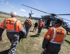 LandSAR personnel walk towards a Royal New Zealand Air Force NH90 helicopter on a nice day. 