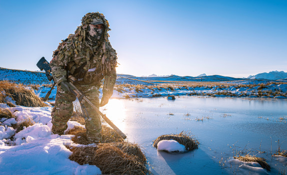 New Zealand Army sniper moves around a water area in the snow in the Tekapo Military Training Area