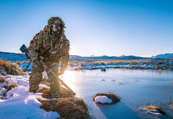 New Zealand Army sniper moves around a water area in the snow in the Tekapo Military Training Area
