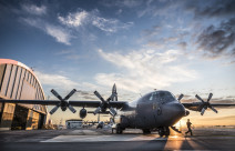 A Royal New Zealand Air Force C-130H(NZ) Hercules aircraft on the flight line at Base Auckland early in the morning as the sun is coming up. One of the Air Loadmasters is walking off the aircraft. In the background to the left you can see the aircraft han