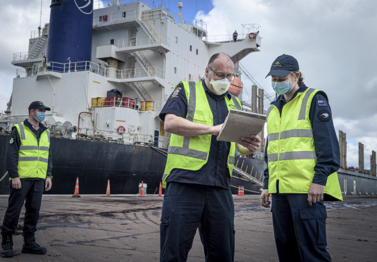 NZDF personnel working with NZ Customs personnel with a ship in the background