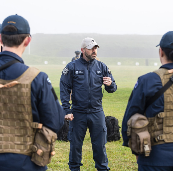 A Royal New Zealand Air Force airman speaks to a group of airmen during training at the range. The day is very misty and wet.