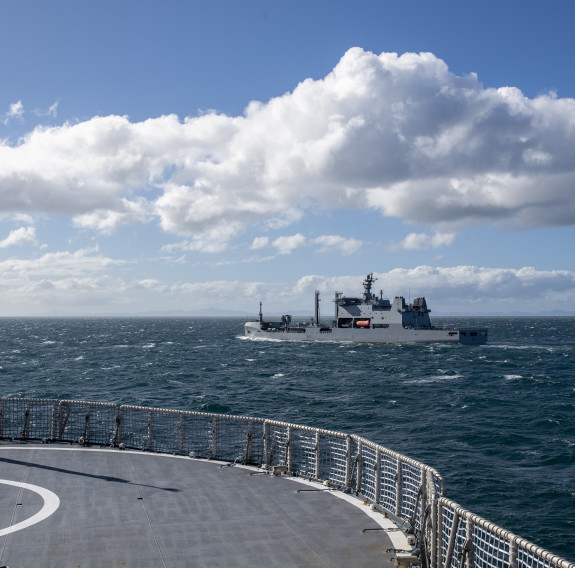 HMNZS Aotearoa transits alongside HMNZS Manawanui sails in the Hauraki Gulf on a sunny day with some cloud in the sky