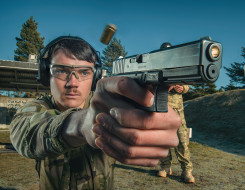 A New Zealand Army soldier fires a Glock G17 Gen 4 with another soldier standing behind them.