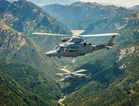 Two A109 helicopters fly over the mountain range. 