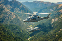 Two A109 helicopters fly over the mountain range. 