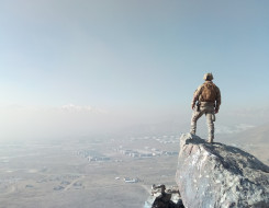 A New Zealand Army solider stands on a rock and looks out over parts of Afghanistan