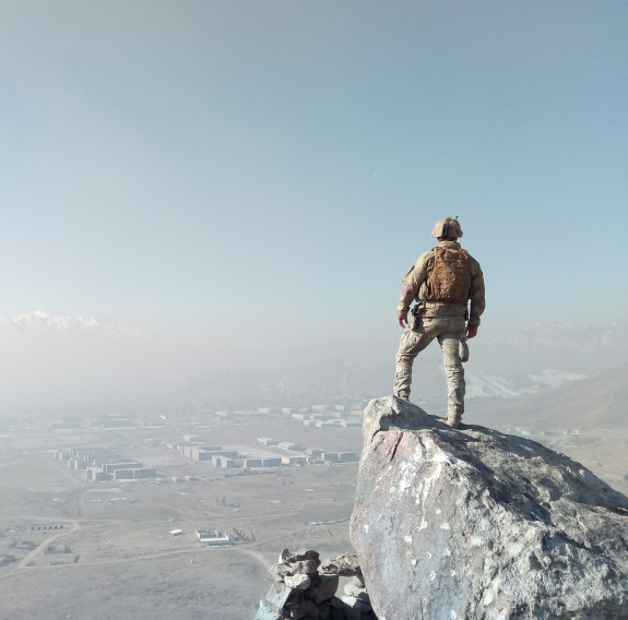 A New Zealand Army solider stands on a rock and looks out over parts of Afghanistan