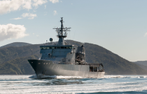 HMNZS Wellington sailing through the Marlborough Sounds, in the background y