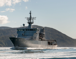 HMNZS Wellington sailing through the Marlborough Sounds, in the background y