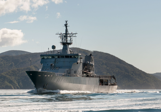 HMNZS Wellington sailing through the Marlborough Sounds, in the background y
