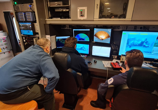 Crew of HMNZS Manawanui review underwater footage of a plane staged on the seabed during the recovery exercise.