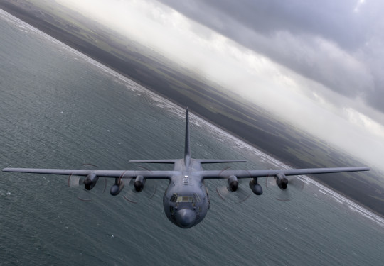 A C-130H(NZ) Hercules banking while flying over ocean.