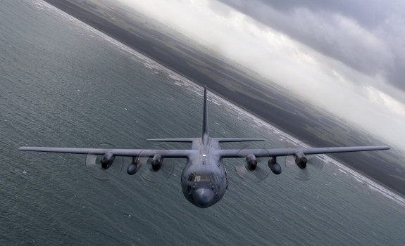 A C-130H(NZ) Hercules banking while flying over ocean.