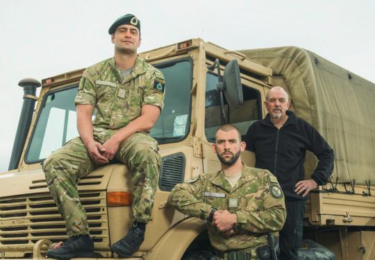 Army personnel pictured standing in front of an Army Unimog, looking at the camera