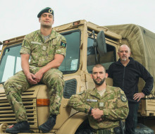 Army personnel pictured standing in front of an Army Unimog, looking at the camera