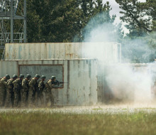 Soldiers in a line, standing back as they prepare to enter an urban setup during Exercise Foxhound