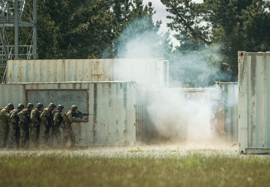 Soldiers in a line, standing back as they prepare to enter an urban setup during Exercise Foxhound