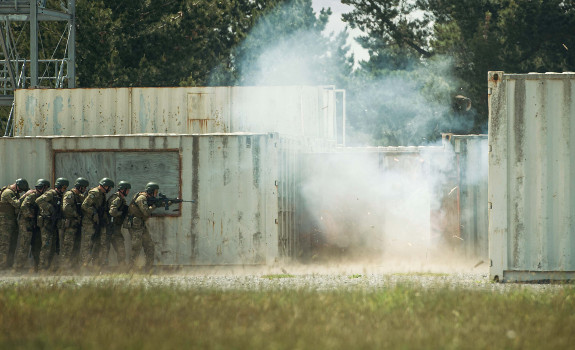 Soldiers in a line, standing back as they prepare to enter an urban setup during Exercise Foxhound