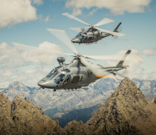 Two A109 helicopters fly over the mountain range.