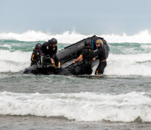 HMNZS Matataua's diving and hydrographic coxswains take a fully-crewed zodiac boat through the surf in the trecherous conditions of Auckland's Piha Beach.