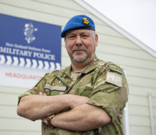 Wing Commander Peel looks at the camera with arms folded.