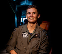 A Royal New Zealand Air Force Air Warfare Officer sits smiling towards the camera