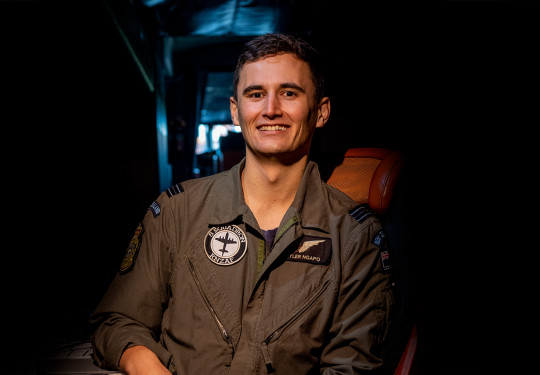 A Royal New Zealand Air Force Air Warfare Officer sits smiling towards the camera