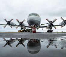 An Orion aircraft on the tarmac with its mirror imagine reflected in the foreground on overcast day at Base Aucklandn