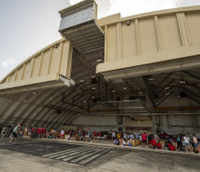 Personnel from a variety of countries pack bundles in a large aircraft hanger in Guam.