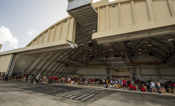Personnel from a variety of countries pack bundles in a large aircraft hanger in Guam.