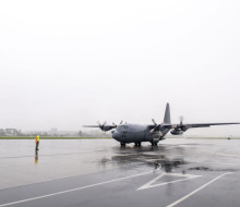 Hercules aircraft on the wet, reflective tarmac of Whenuapai Air Force Base.