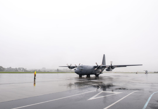 Hercules aircraft on the wet, reflective tarmac of Whenuapai Air Force Base.