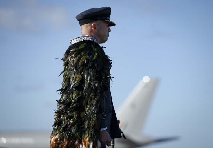 An aviator stands in uniform looking away from the camera. 