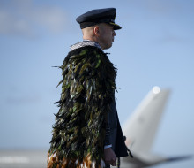 An aviator stands in uniform looking away from the camera. 