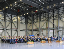 A crowd of people seated in a large aircraft hangar.