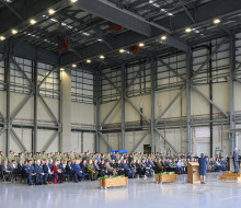 A crowd of people seated in a large aircraft hangar.