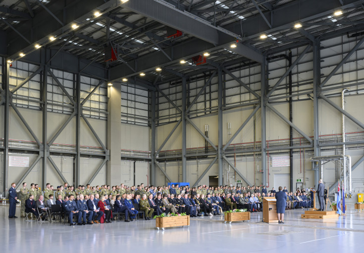 A crowd of people seated in a large aircraft hangar.