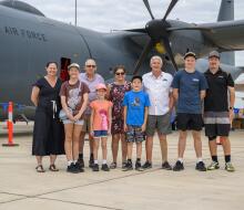A nine-person family photo in front of a Royal Australian Air Force aircraft.