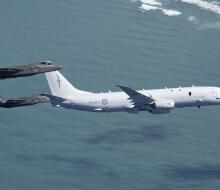 Two RAAF F-35As conducting intercept training with an RNZAF P-8A Poseidon - the aircraft are flying over water. 