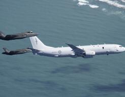 Two RAAF F-35As conducting intercept training with an RNZAF P-8A Poseidon - the aircraft are flying over water. 